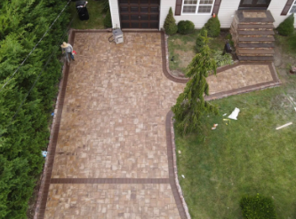 Brick paver driveway and walkway with a dark border. A person stands nearby.