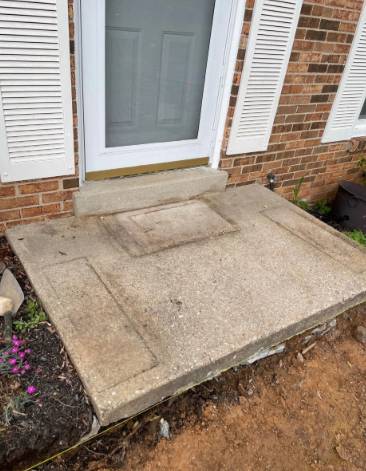Concrete front porch with step leading to a door; brick house with shutters; yard in front.