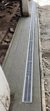 Concrete drainage channel installed along a building's foundation.
