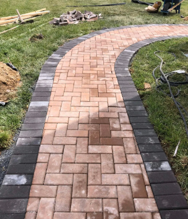 Brick pathway winding through grass, with dark border bricks.