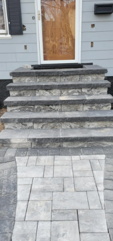 Gray stone steps leading to a front door with a glass panel; gray stone walkway.