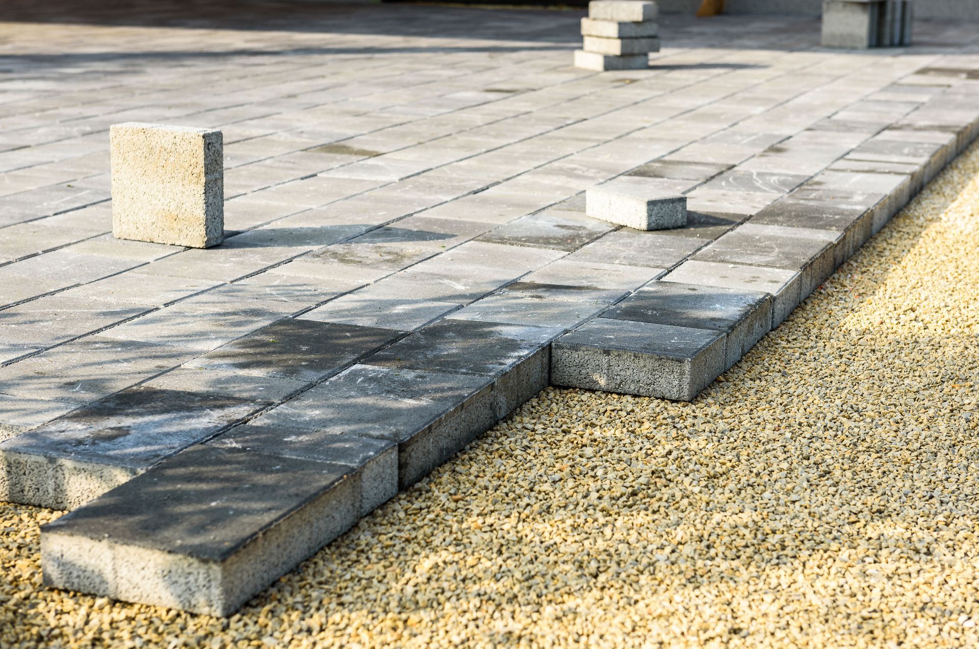 Concrete pavers being laid on a gravel base, outdoor patio construction.