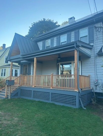 Two-story house with gray siding, a newly built wooden porch and dark gray roof.