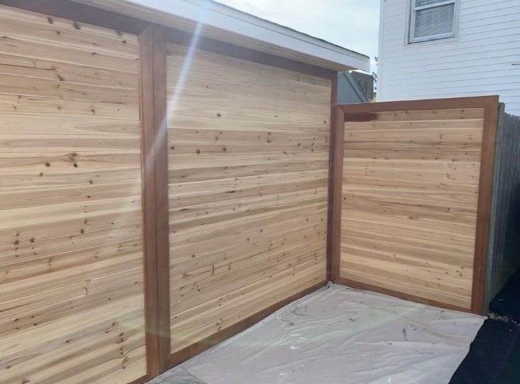 Wooden privacy fence with horizontal planks, brown trim, and a white building.