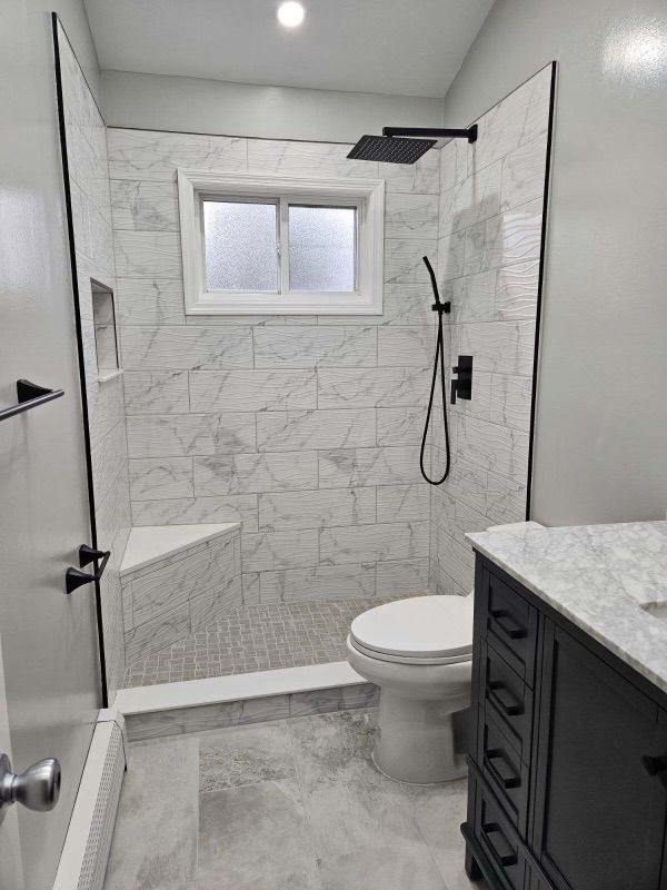 Bathroom with marble tile shower, black fixtures, and a toilet.