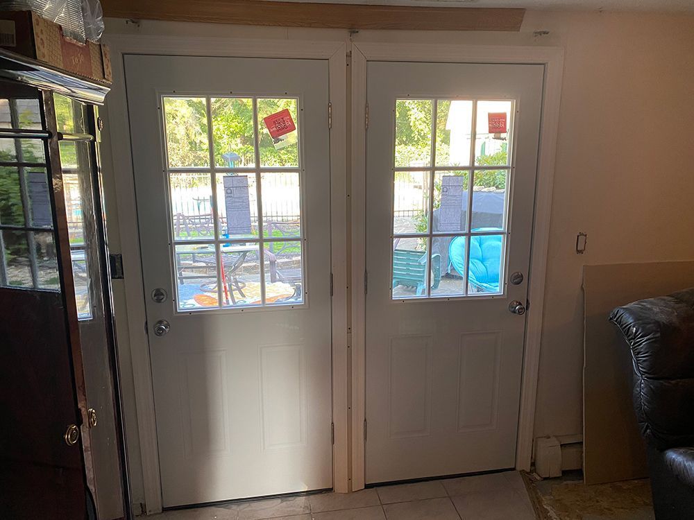 Two white French doors with glass panes, leading outside.
