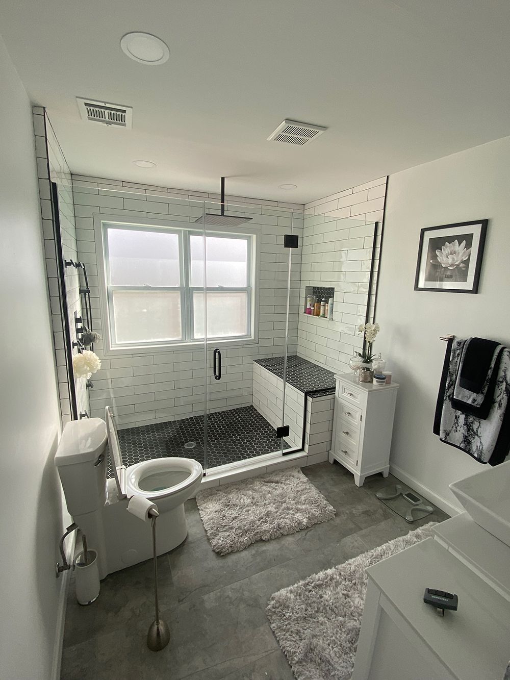 Modern bathroom with shower, toilet, white vanity, and gray floor.