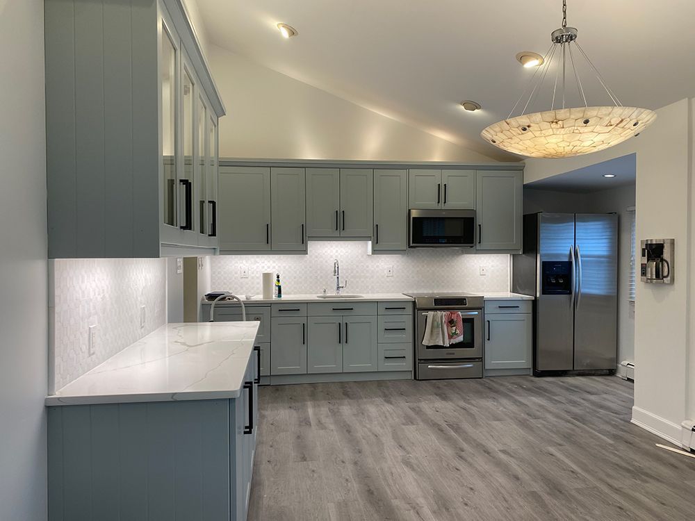 Modern kitchen with blue-gray cabinets, stainless steel appliances, and gray flooring.