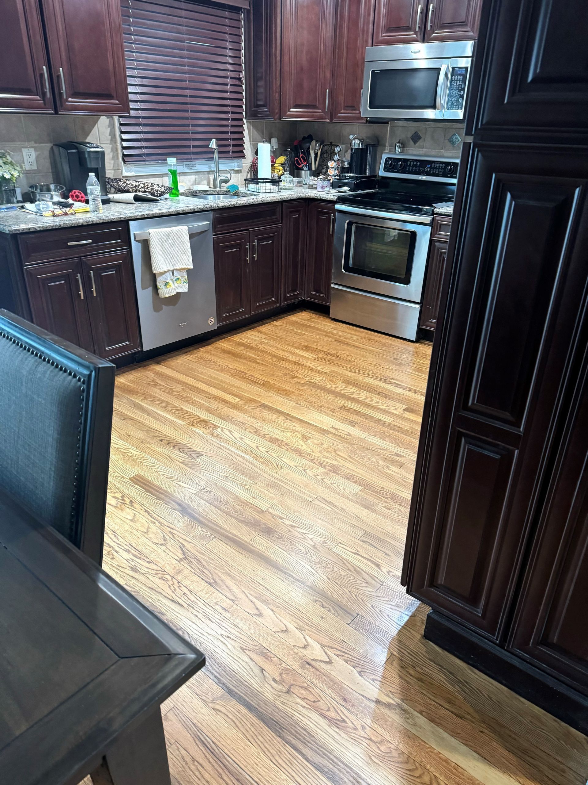 Kitchen with brown cabinets, stainless steel appliances, and wooden flooring.