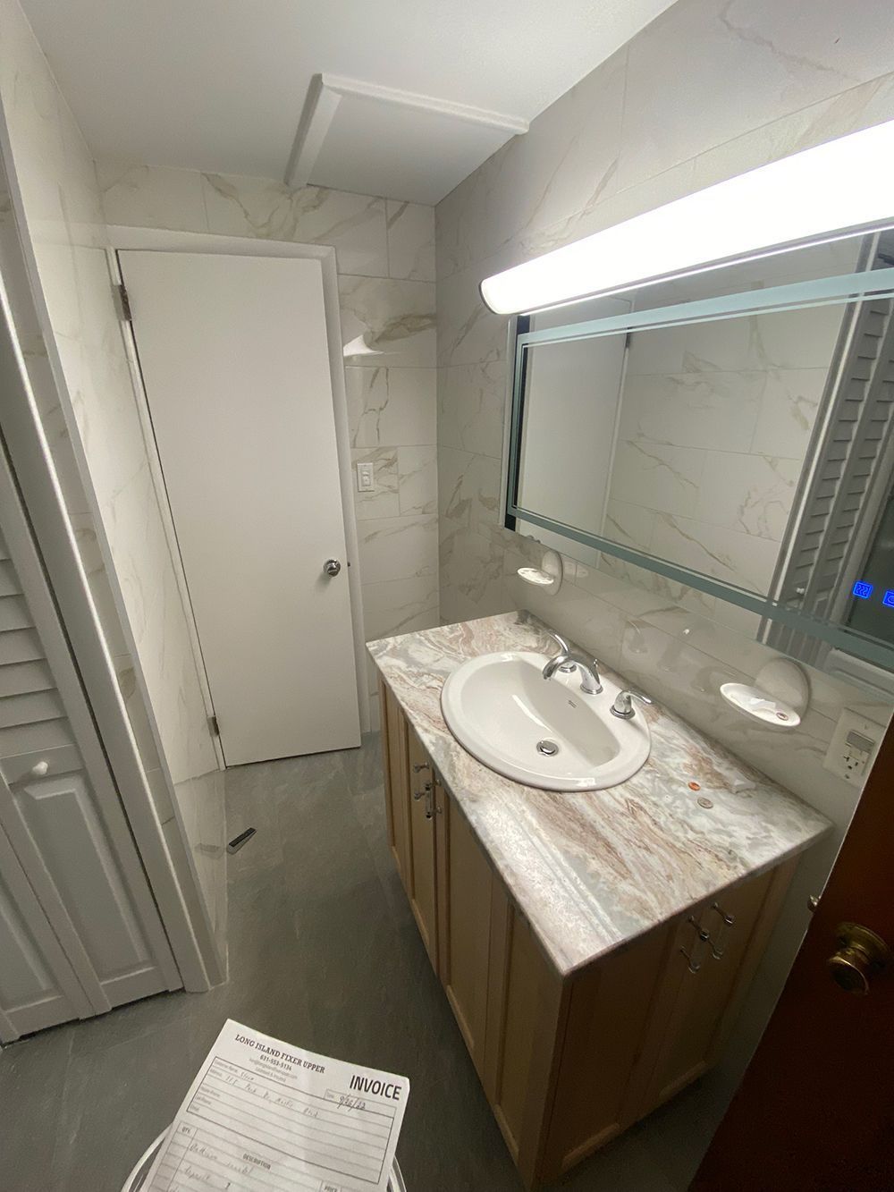Bathroom with white walls, vanity, mirror, and a door.