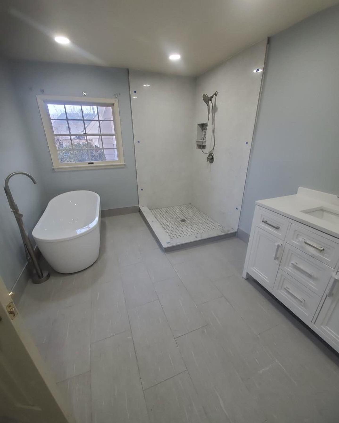 Modern bathroom with freestanding tub, tiled shower, and white vanity.