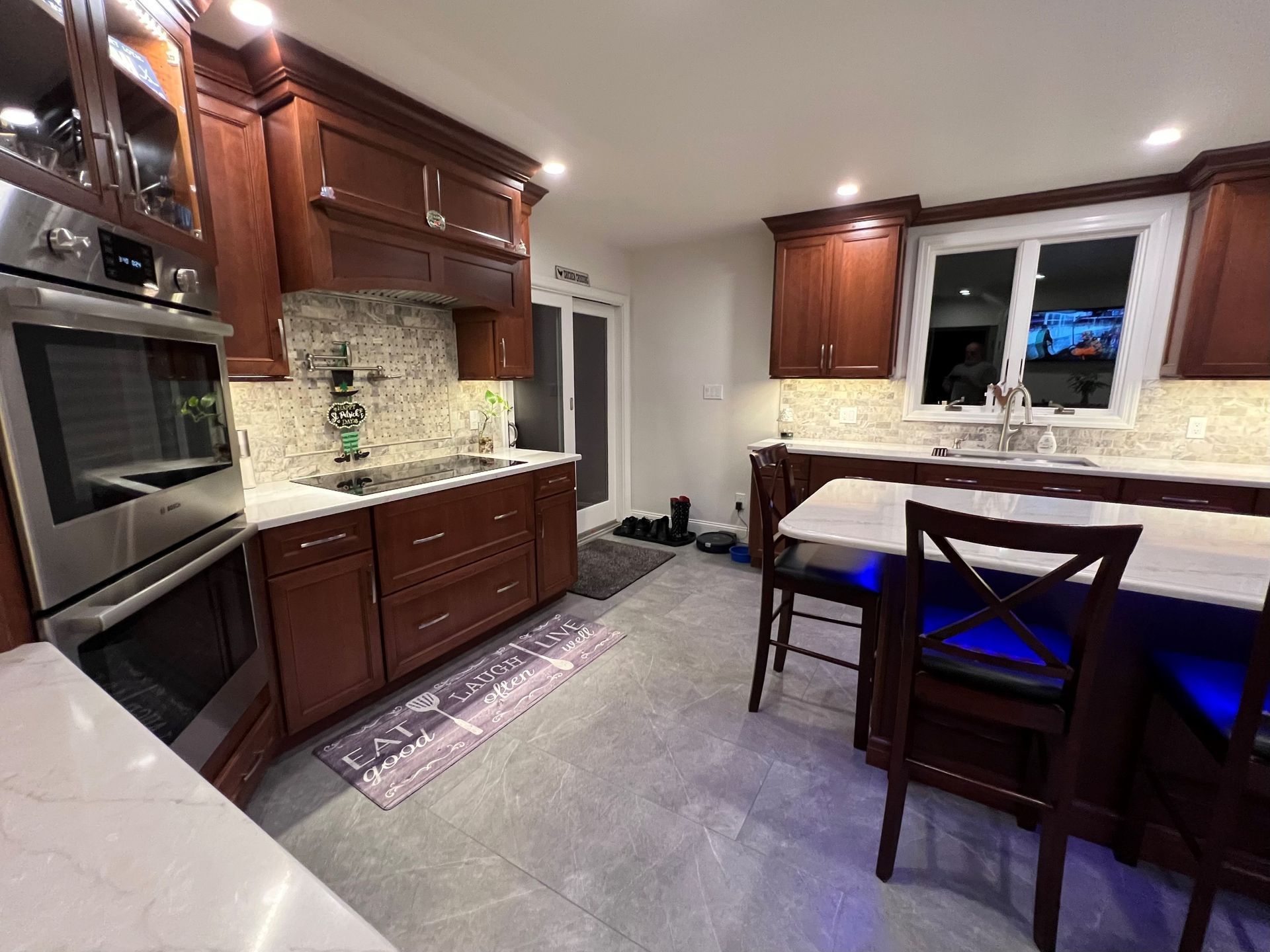Kitchen with cherry cabinets, stainless steel appliances, and a white countertop island.