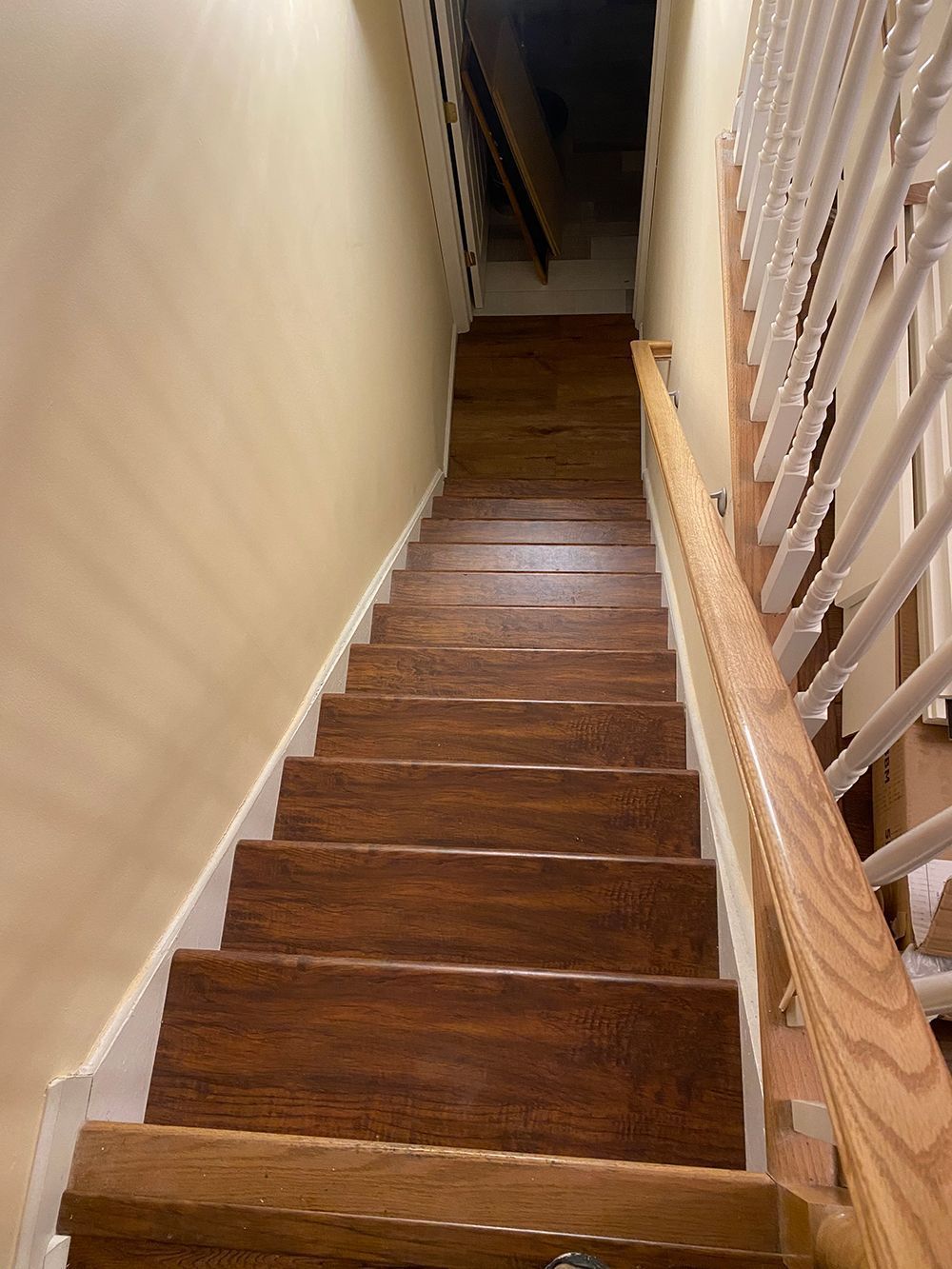 Wooden staircase with a wooden handrail and white trim, going upward.