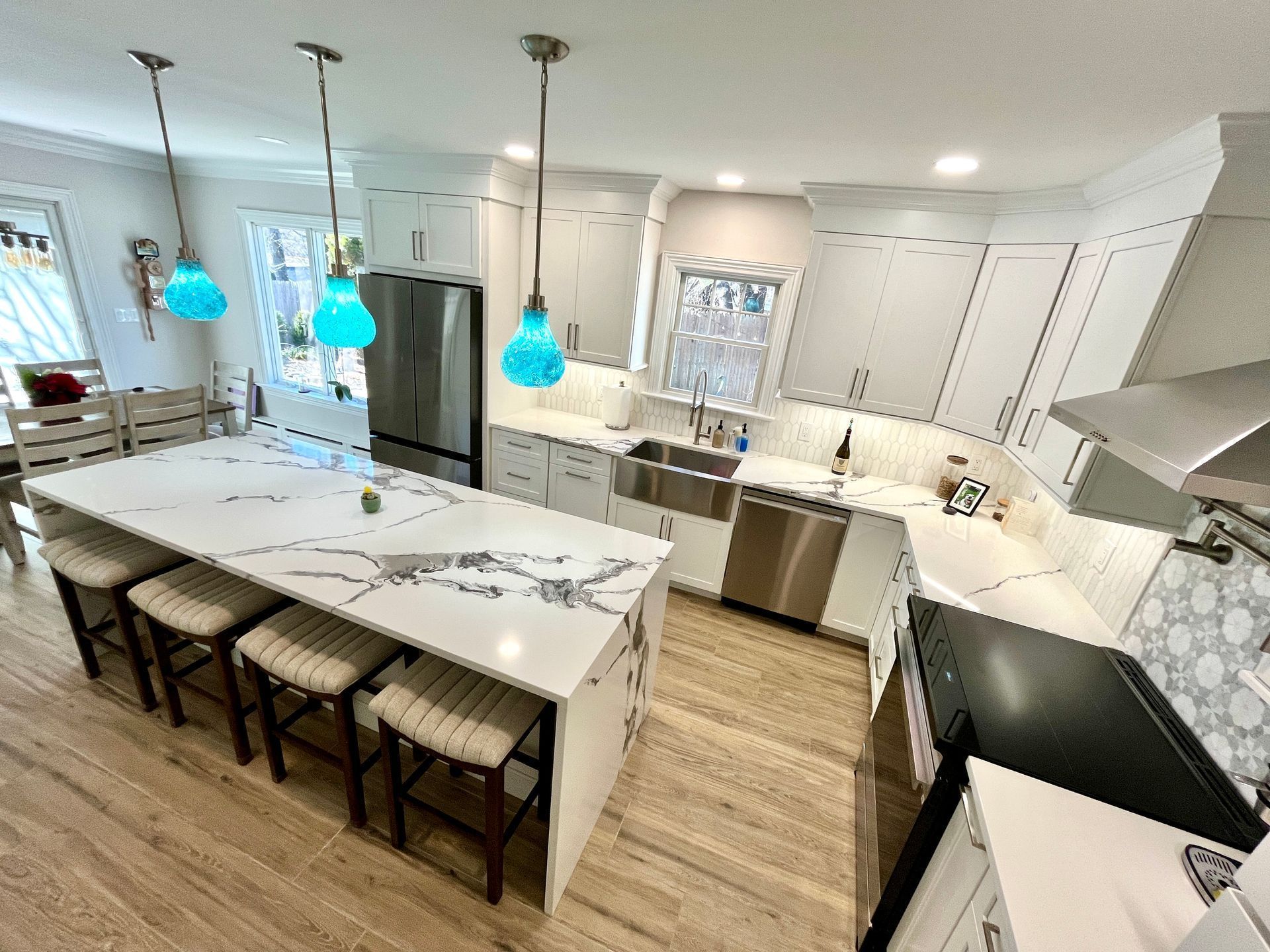Modern white kitchen with a large island and blue pendant lights.