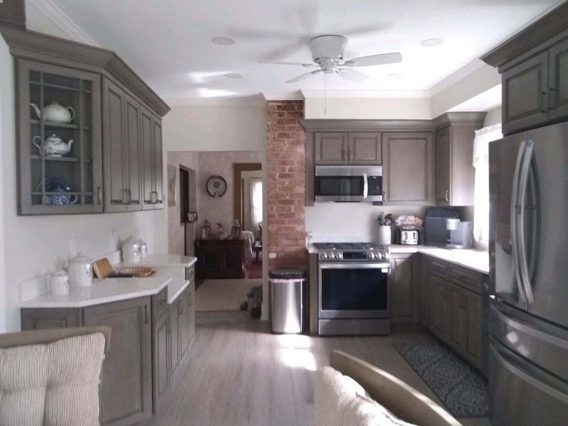 Kitchen with gray cabinets, stainless steel appliances, and a red brick column.