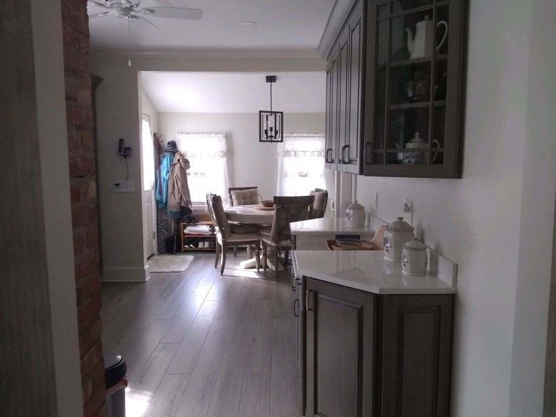Kitchen with wood floor, cabinets, and dining area in the background.