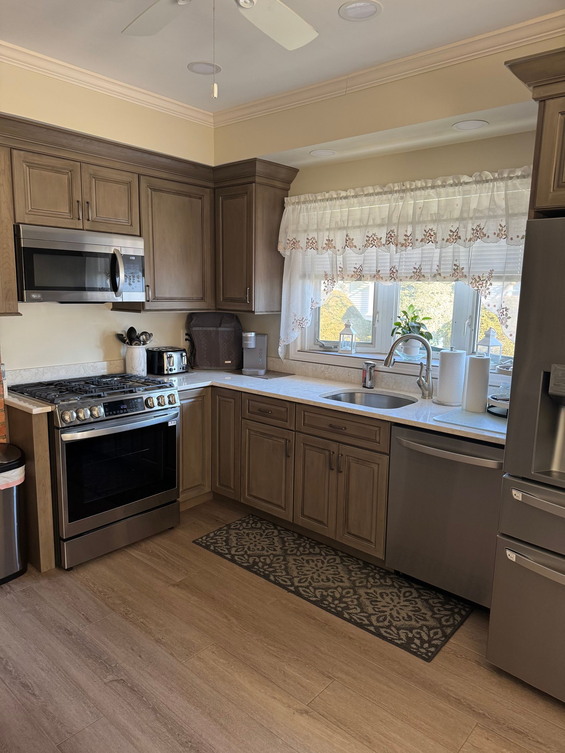 Kitchen with gray cabinets, stainless steel appliances, and a window with a floral valance.