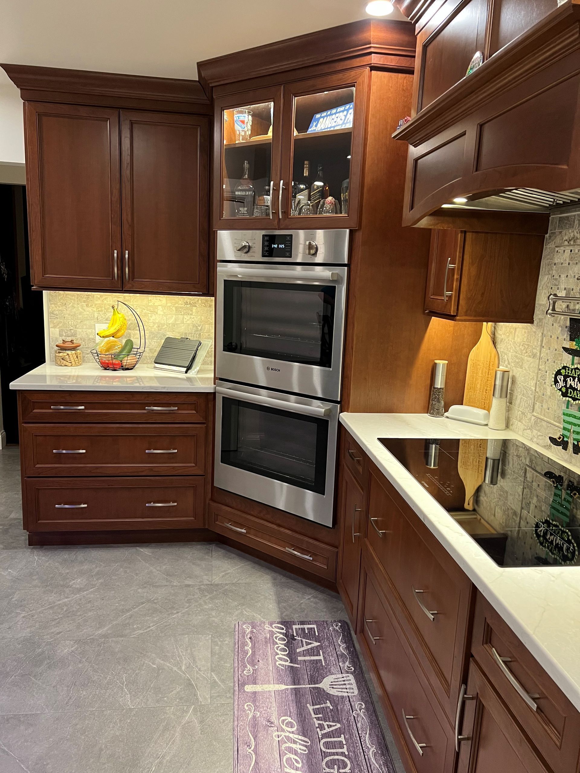 Kitchen with brown cabinets, stainless steel double oven, and white countertops.
