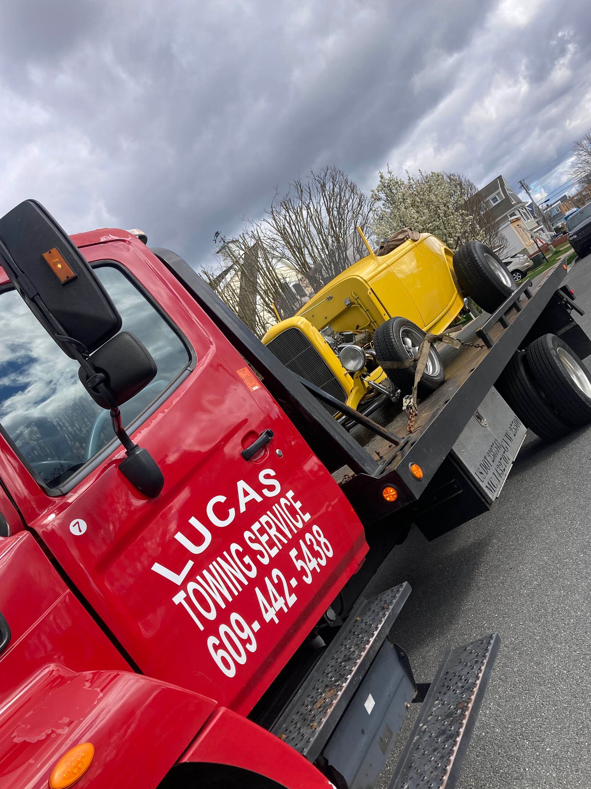 A red tow truck with a yellow car on the back of it