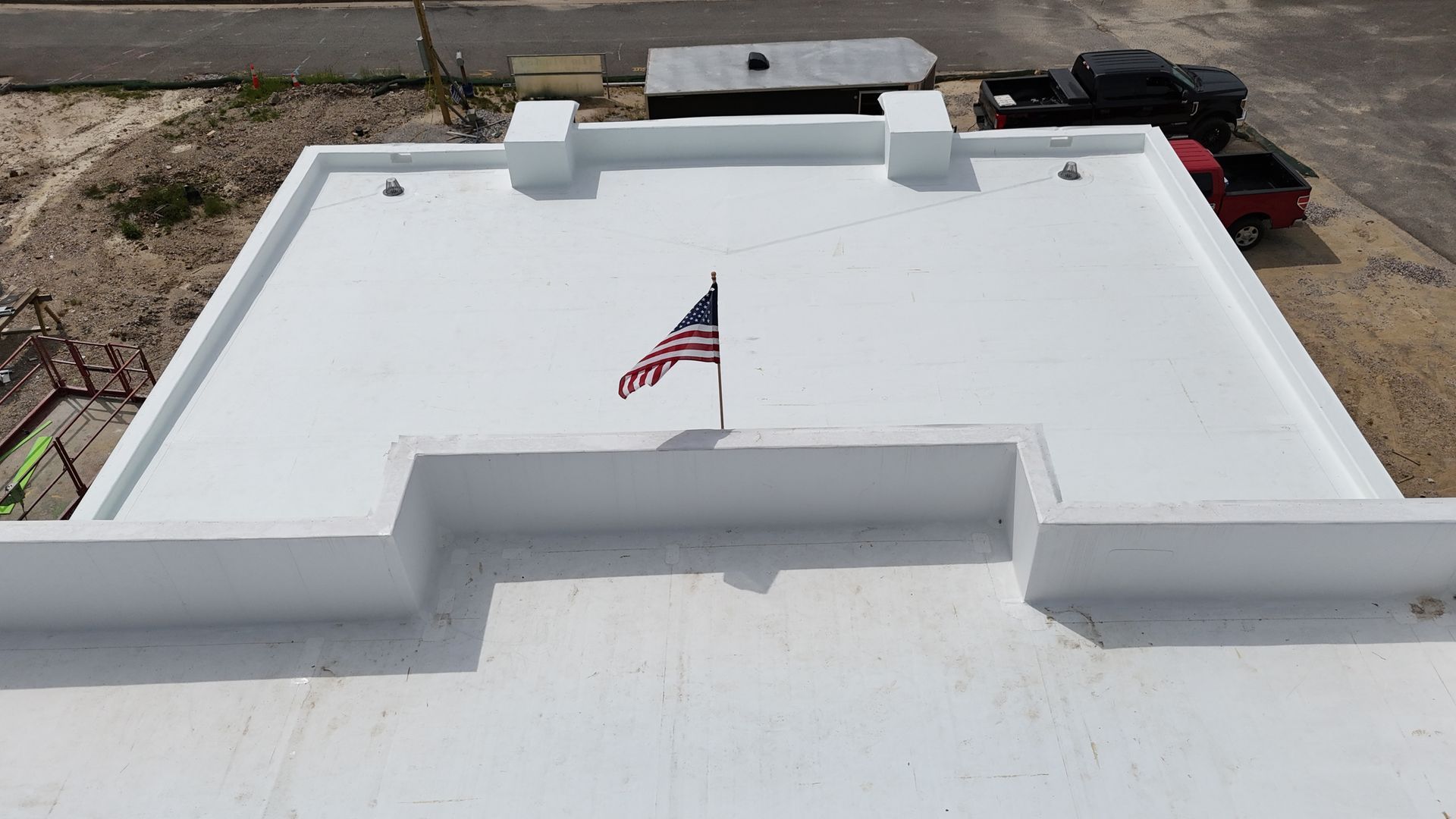 An American flag waves on a white rooftop.