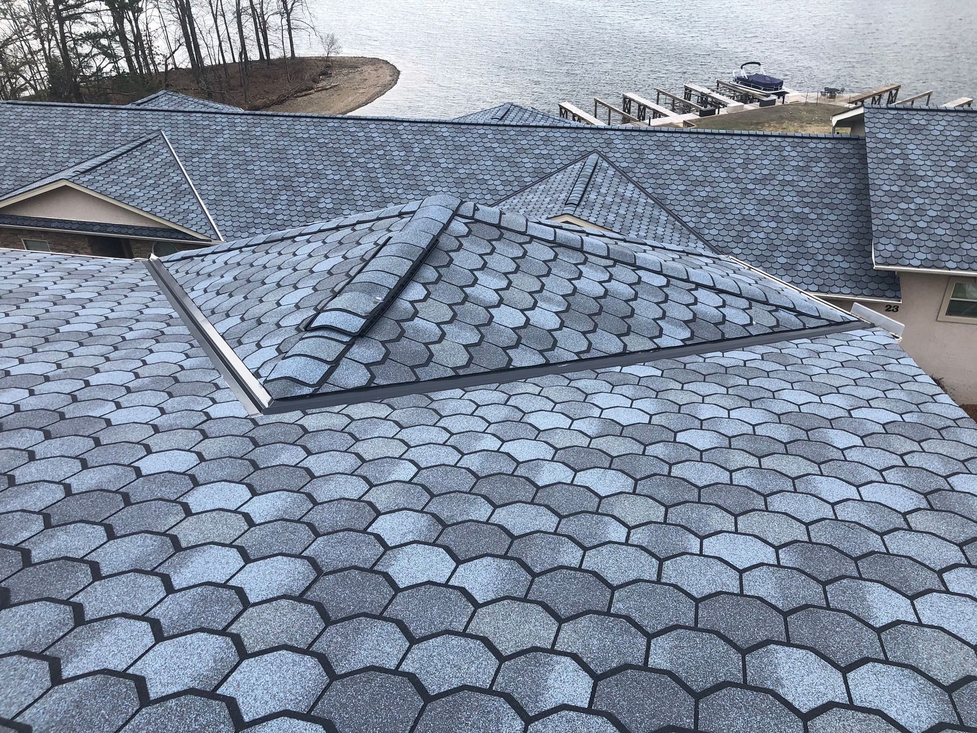 Gray and blue scalloped roof with water and boats in the background.