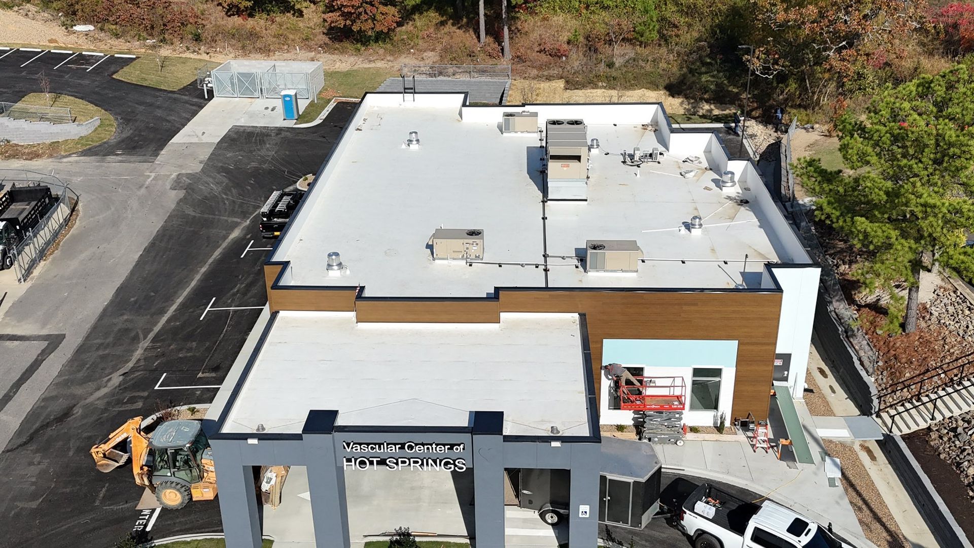 Aerial view of a commercial building with a flat white roof and a brown and blue facade.