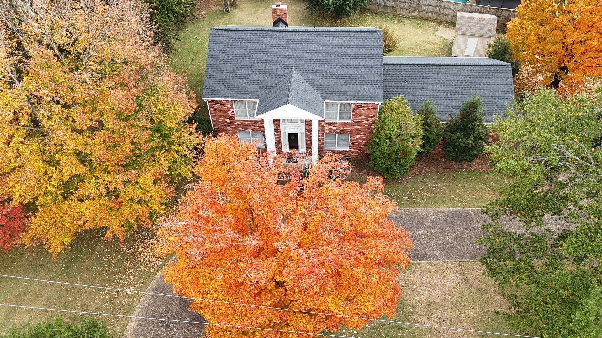 House surrounded by trees with autumn foliage; orange, yellow, and red colors.