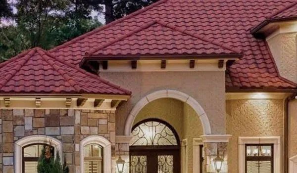 Beige stucco house with a red tile roof and stone accents.