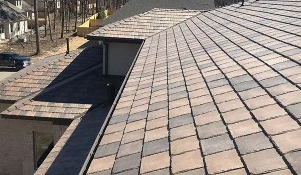 Close-up of a clay tile roof with a mix of brown and gray tiles, angled slightly from above.