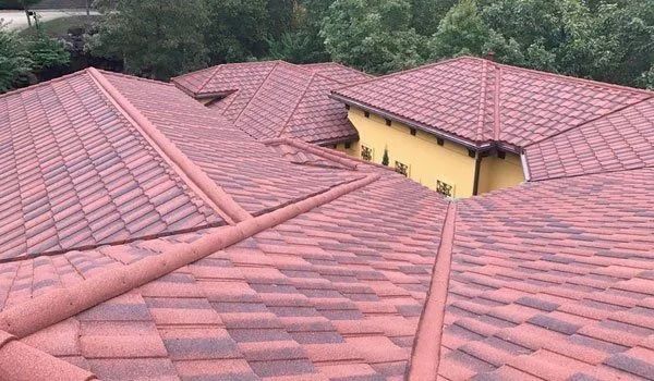 Red tile roof of a building with multiple sections, surrounded by trees.