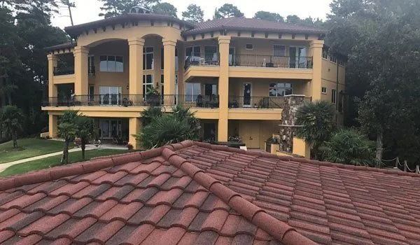 Large yellow house with red-tiled roof, surrounded by trees.