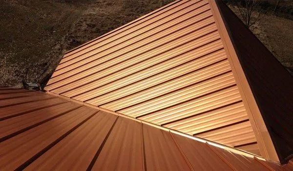 Copper metal roof with angled ridges and side panels.