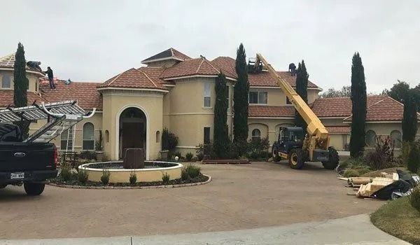 House roof being repaired by workers using a forklift on a cloudy day.