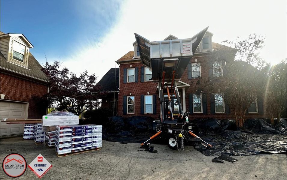 Fire-damaged brick house with construction lift, debris, and stacked materials in front yard