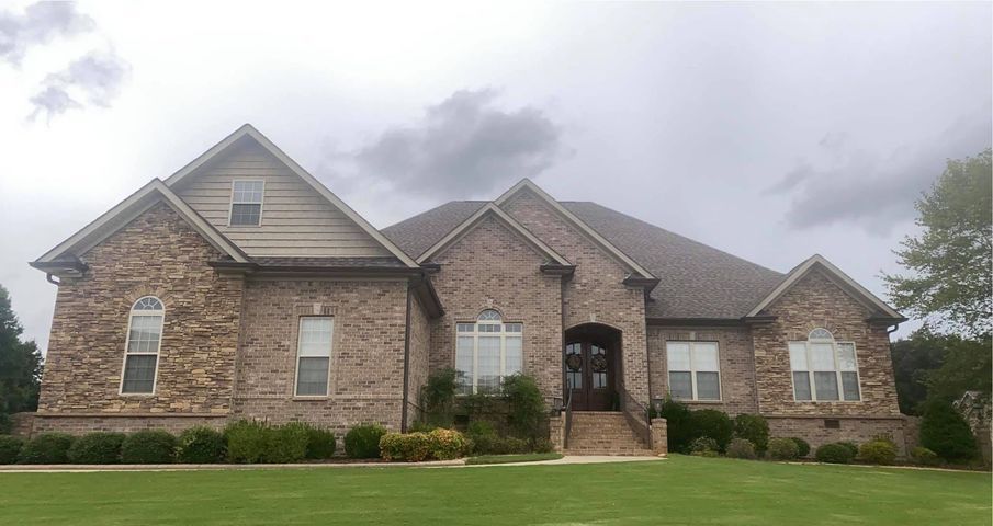 Brick suburban house with a front lawn and cloudy sky