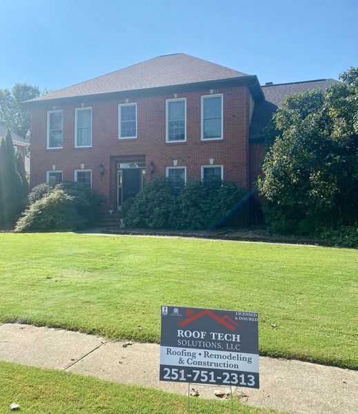 Brick office building with lawn and a Roof Tech sign in front