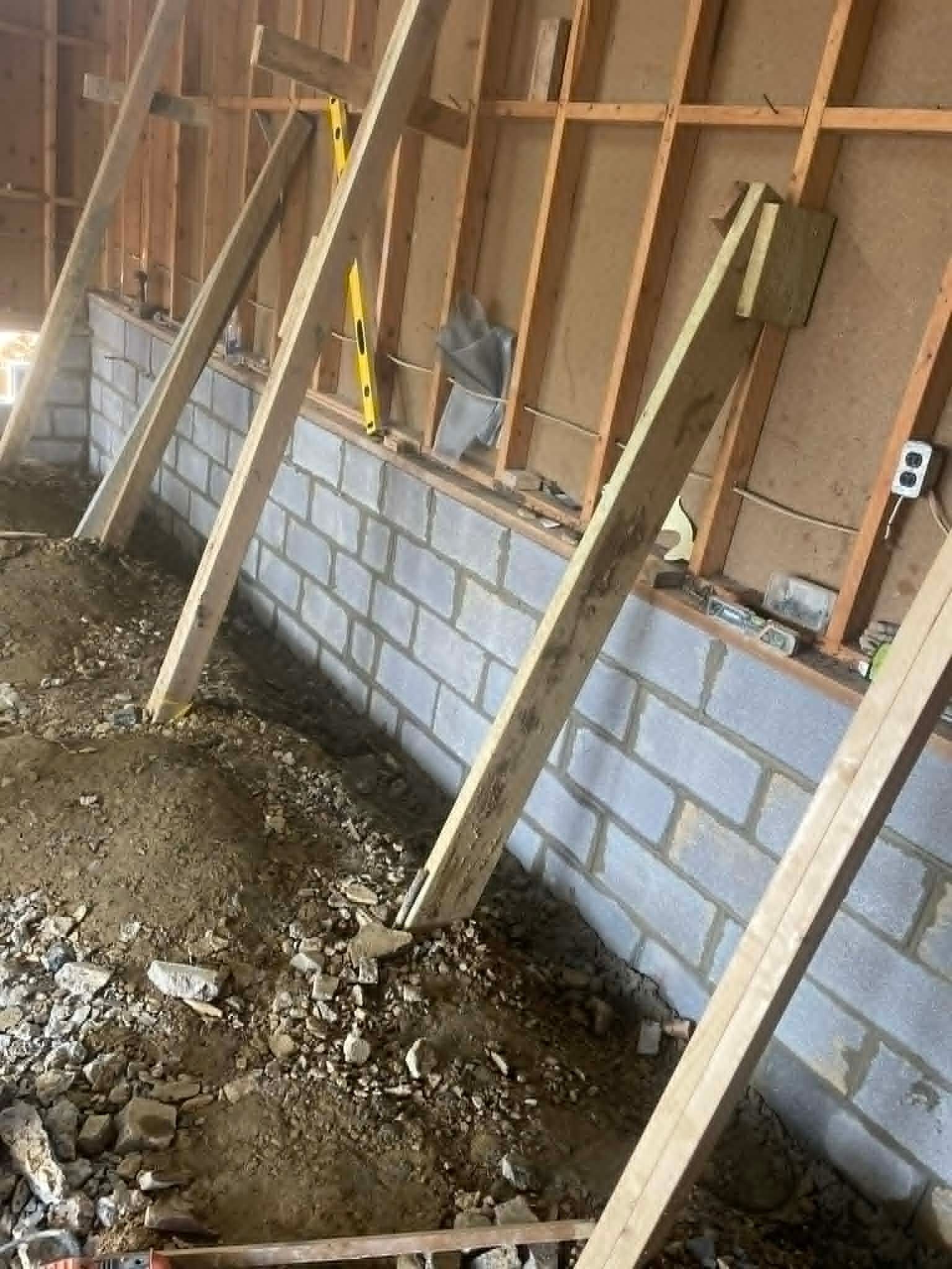 Partially built interior wall with cinder blocks and wooden support braces in a construction site