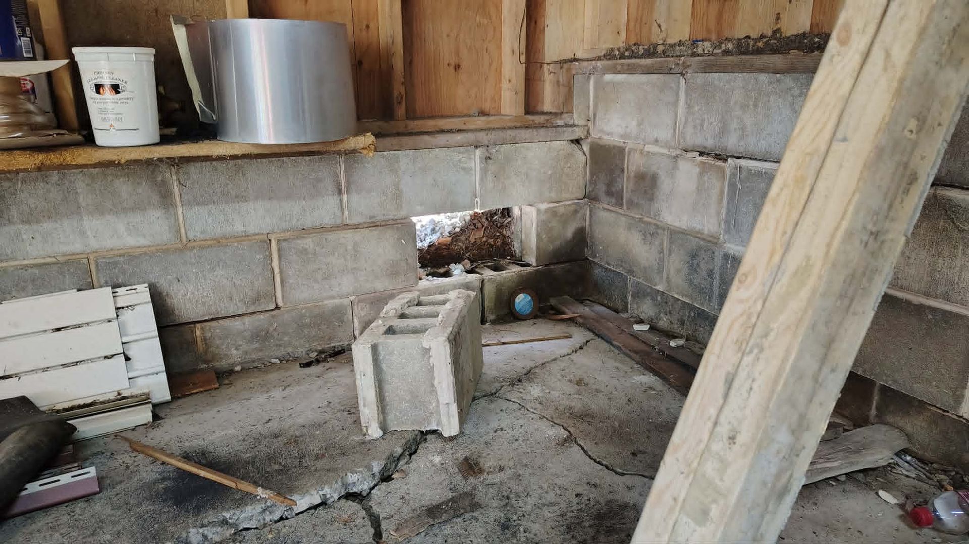 Unfinished room with cinder block walls, wood framing, buckets, and construction materials on the floor.