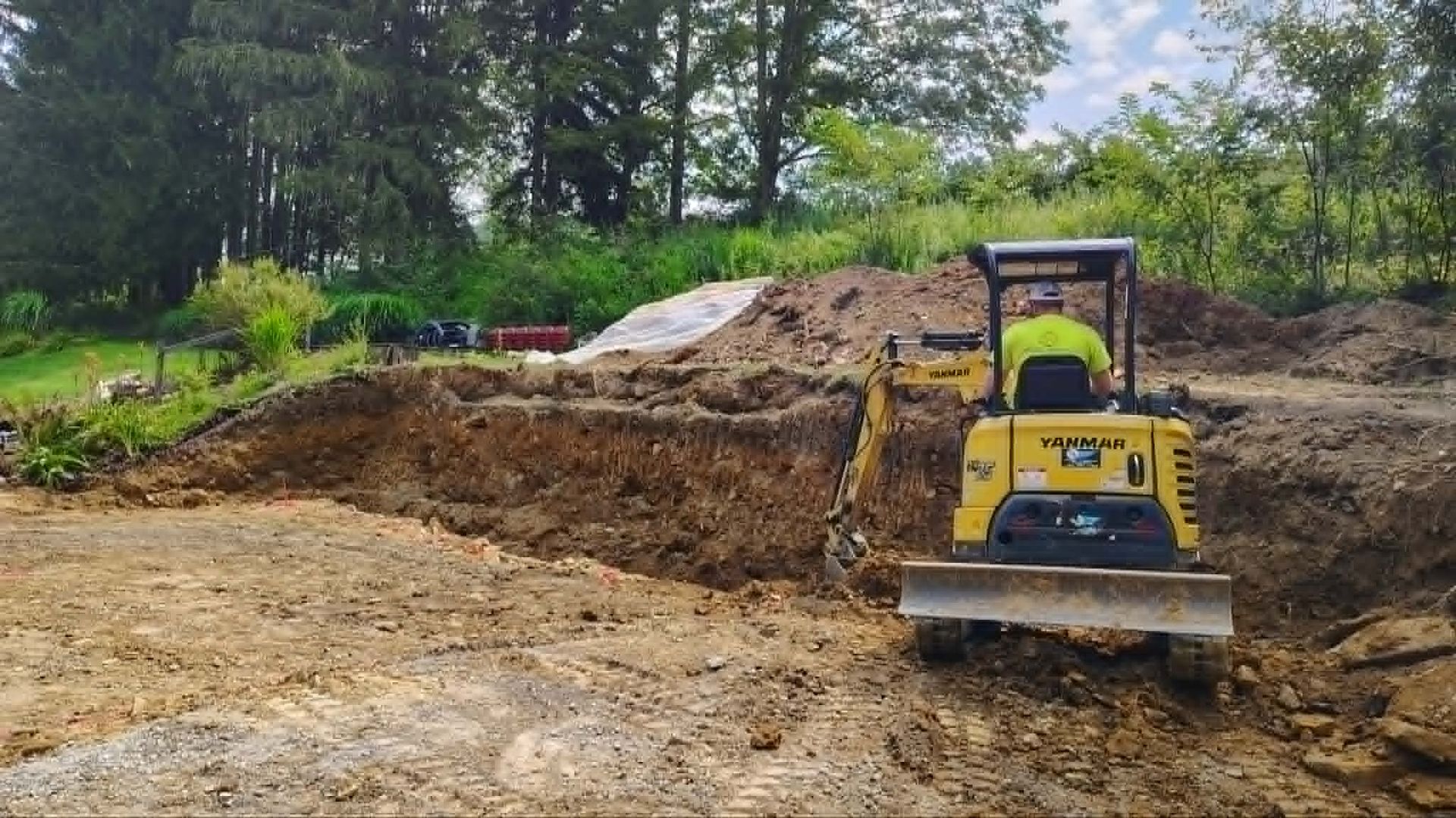 Yellow bulldozer leveling dirt on a muddy construction site with trees in the background