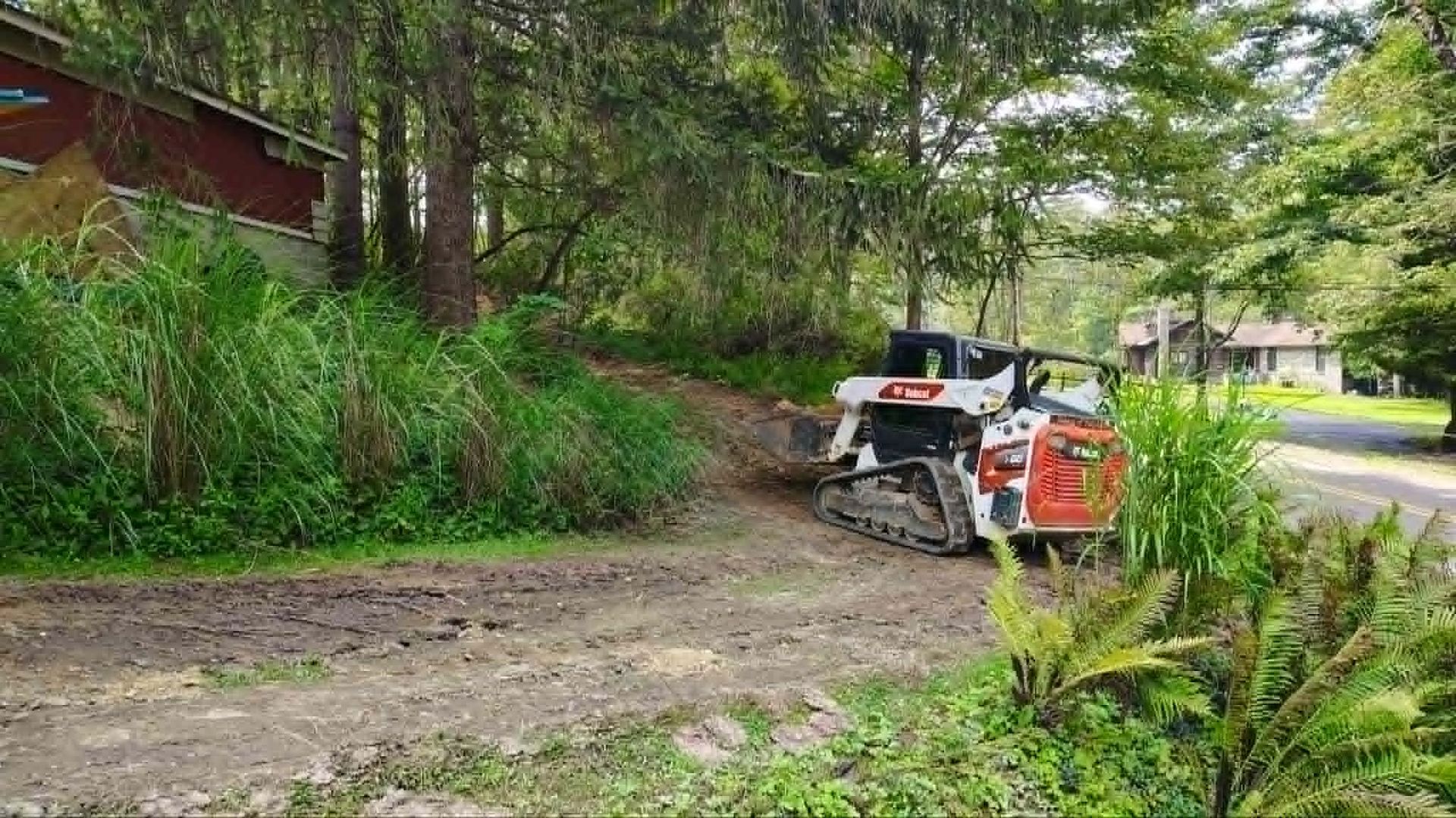Rally car turning on a muddy forest road beside trees and grass