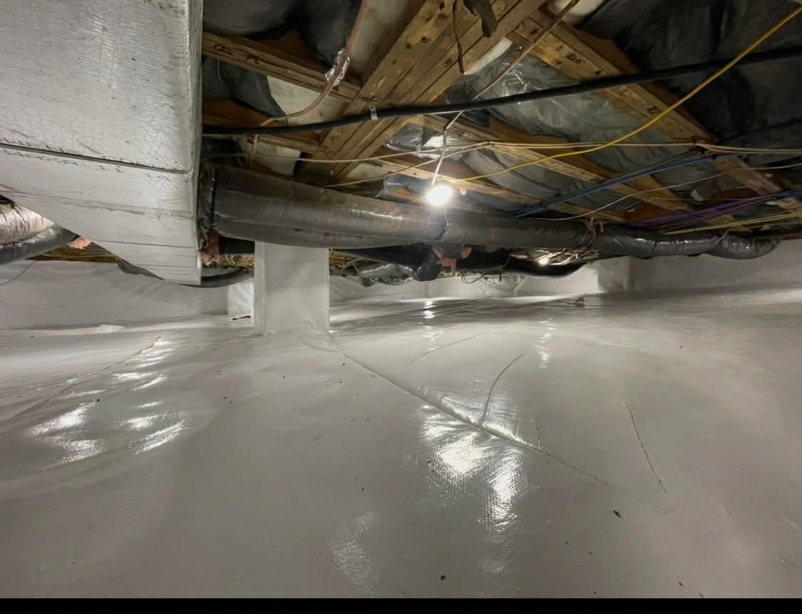 Damaged basement ceiling with exposed pipes and wiring above a wet white floor