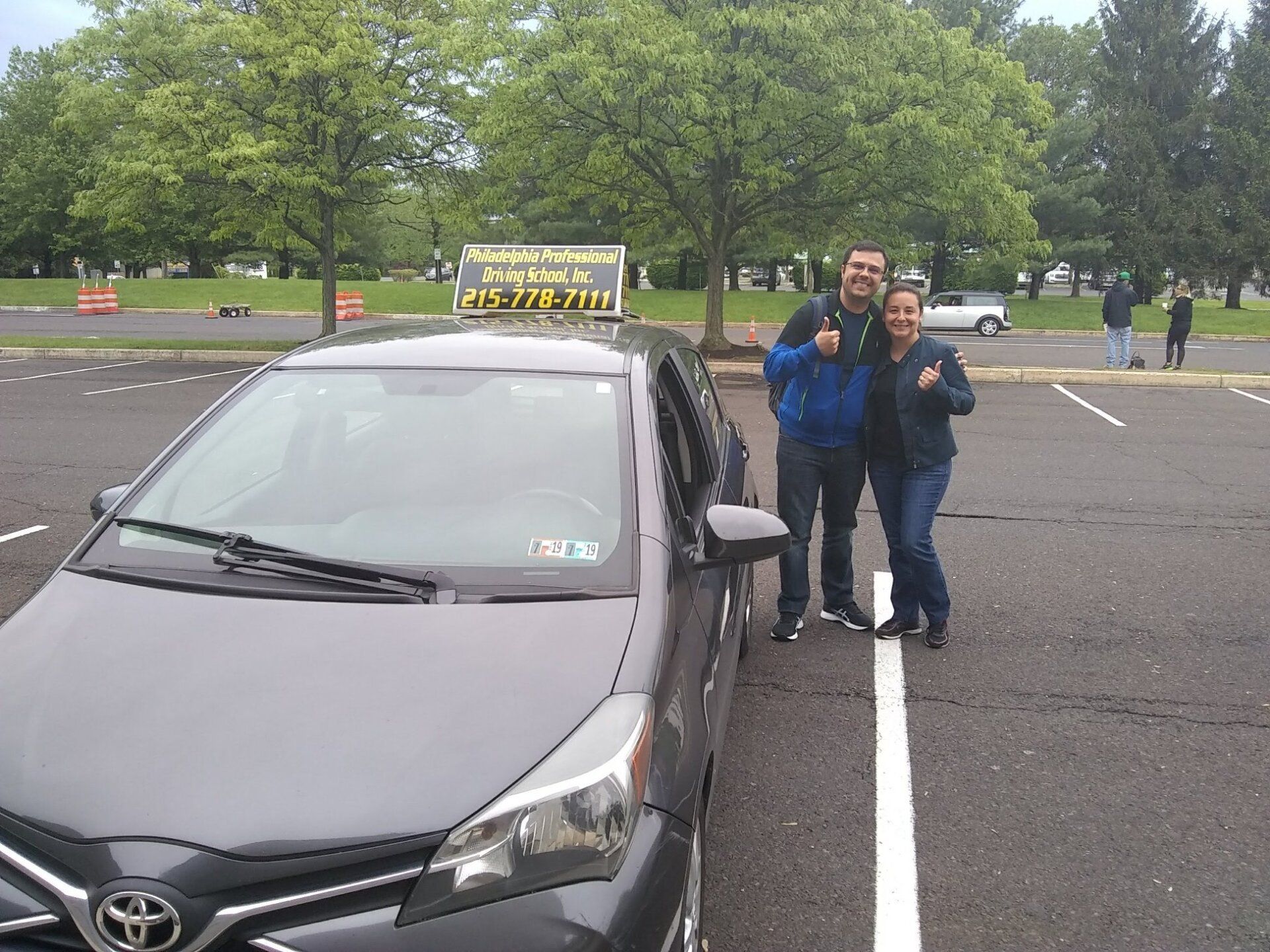 Man and woman doing ok sign after passing driving school test