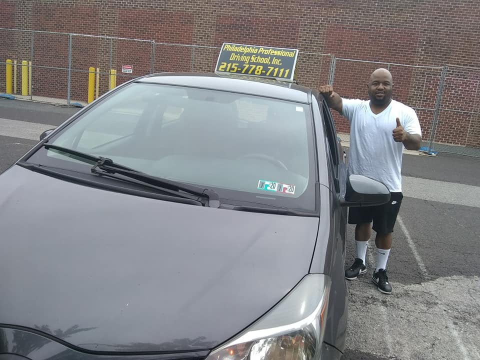 Man in white shirt doing ok sign after passing driving school test