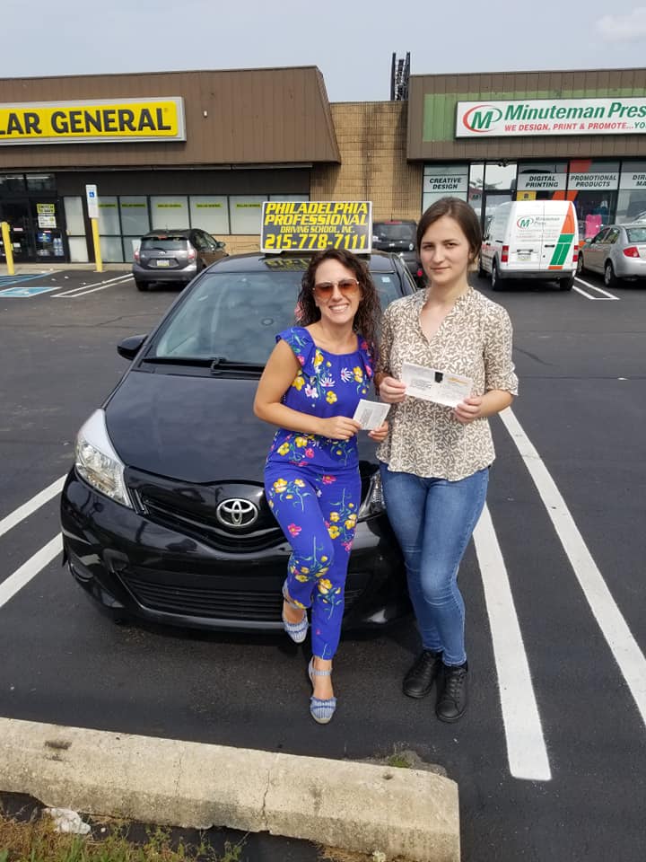 Two female holding paper after successfully passing driving school test