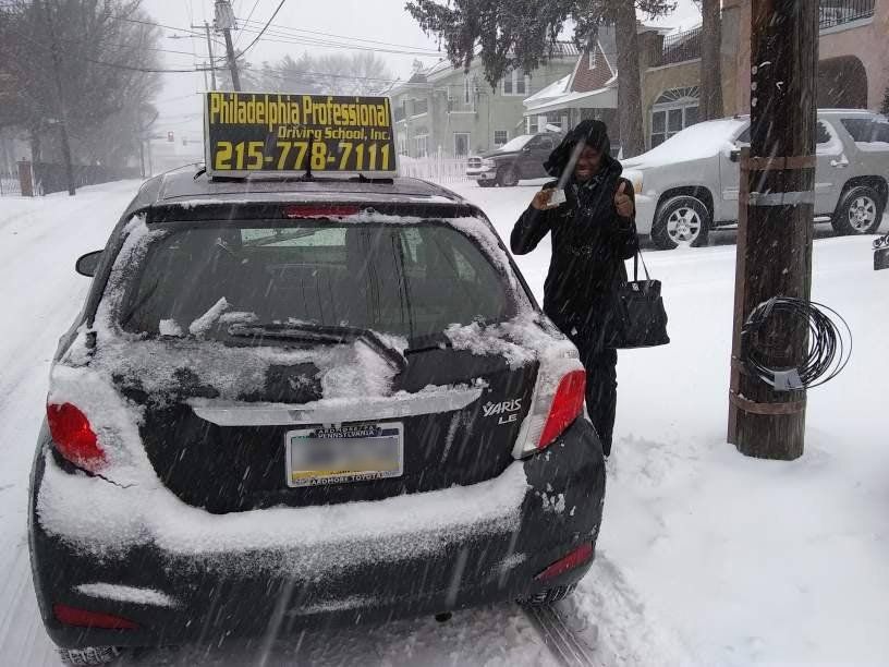 Smiling woman doing ok sign after passing driving school test on a snowy day