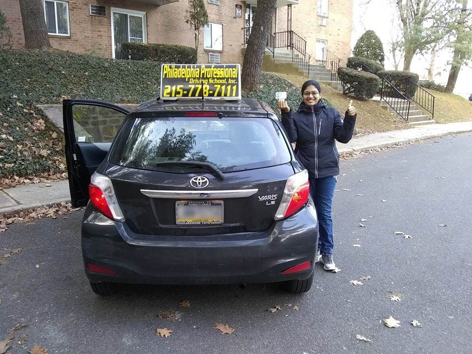 Female holding driver's license and doing ok sign after passing driving school test