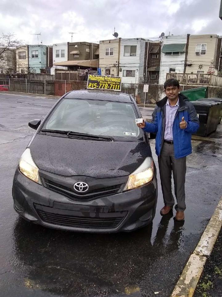 Man wearing blue jacket holding driver's license and doing ok sign