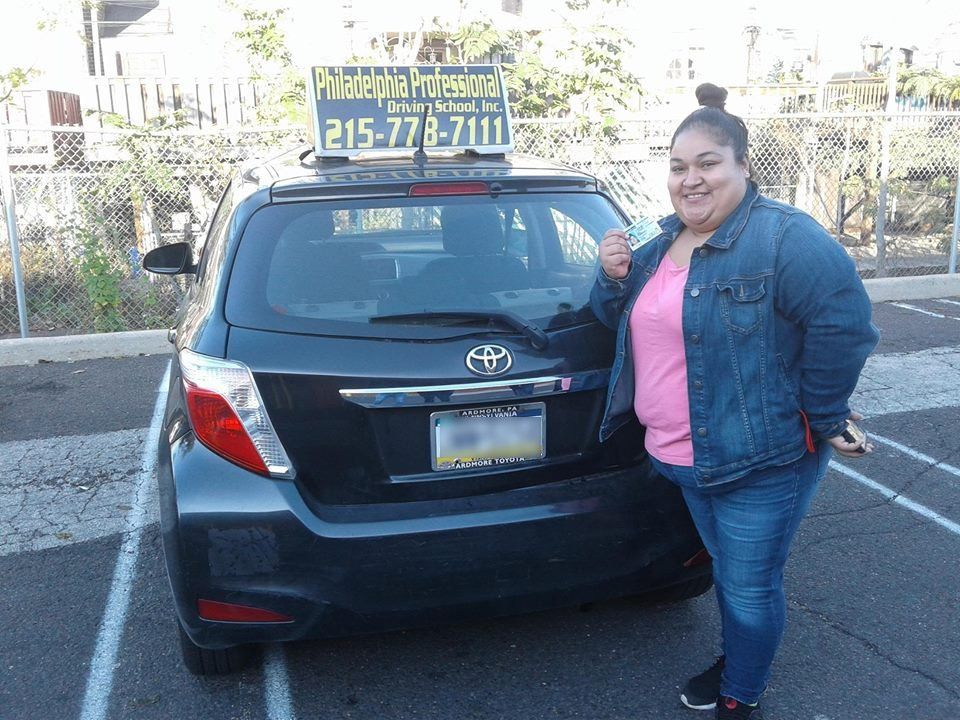 Woman in pink shirt holding driver's license after passing driving school test