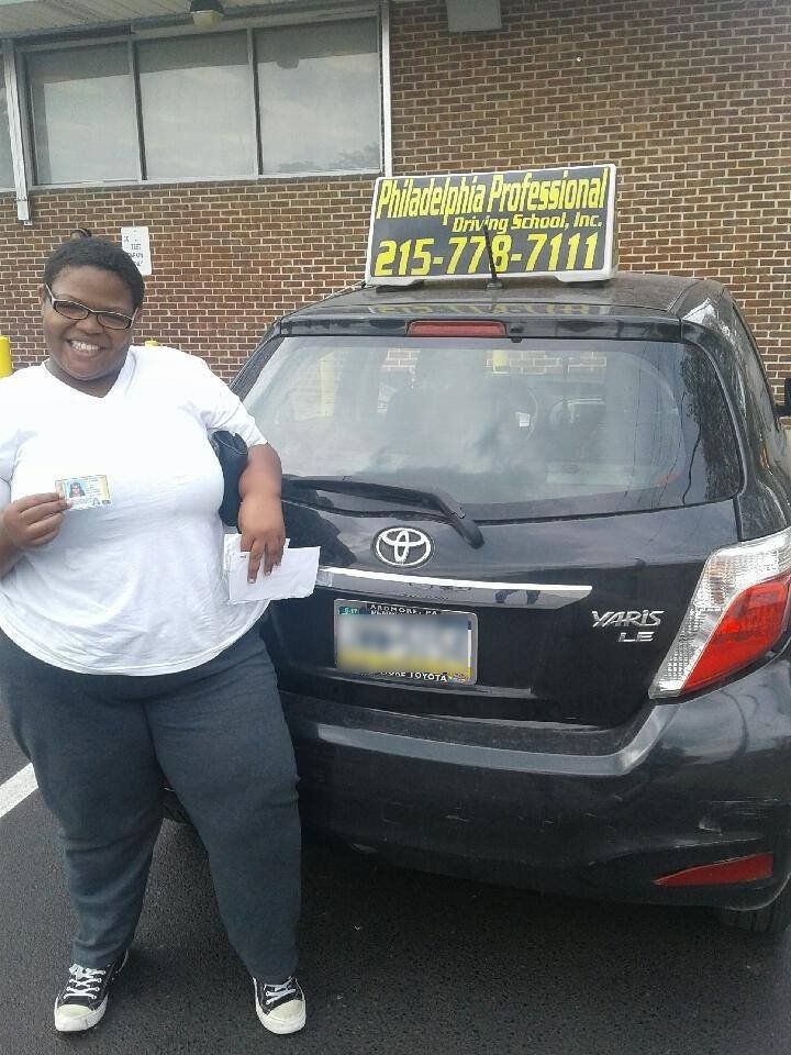 Smiling woman in white shirt holding driver's license