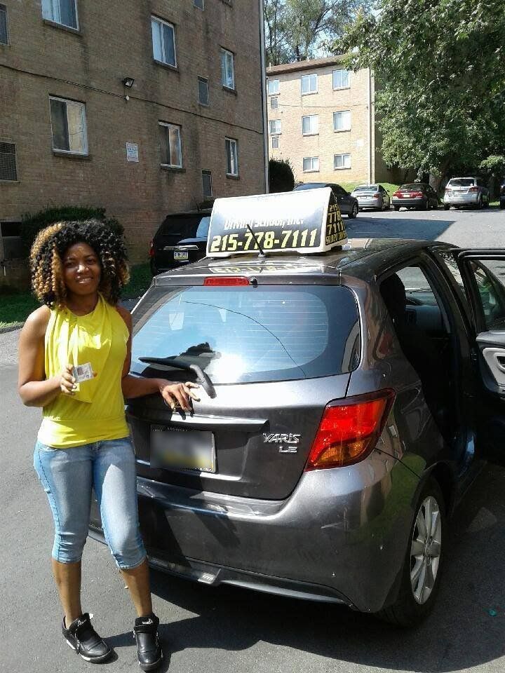 Woman in yellow top holding driver's license after passing driving school test